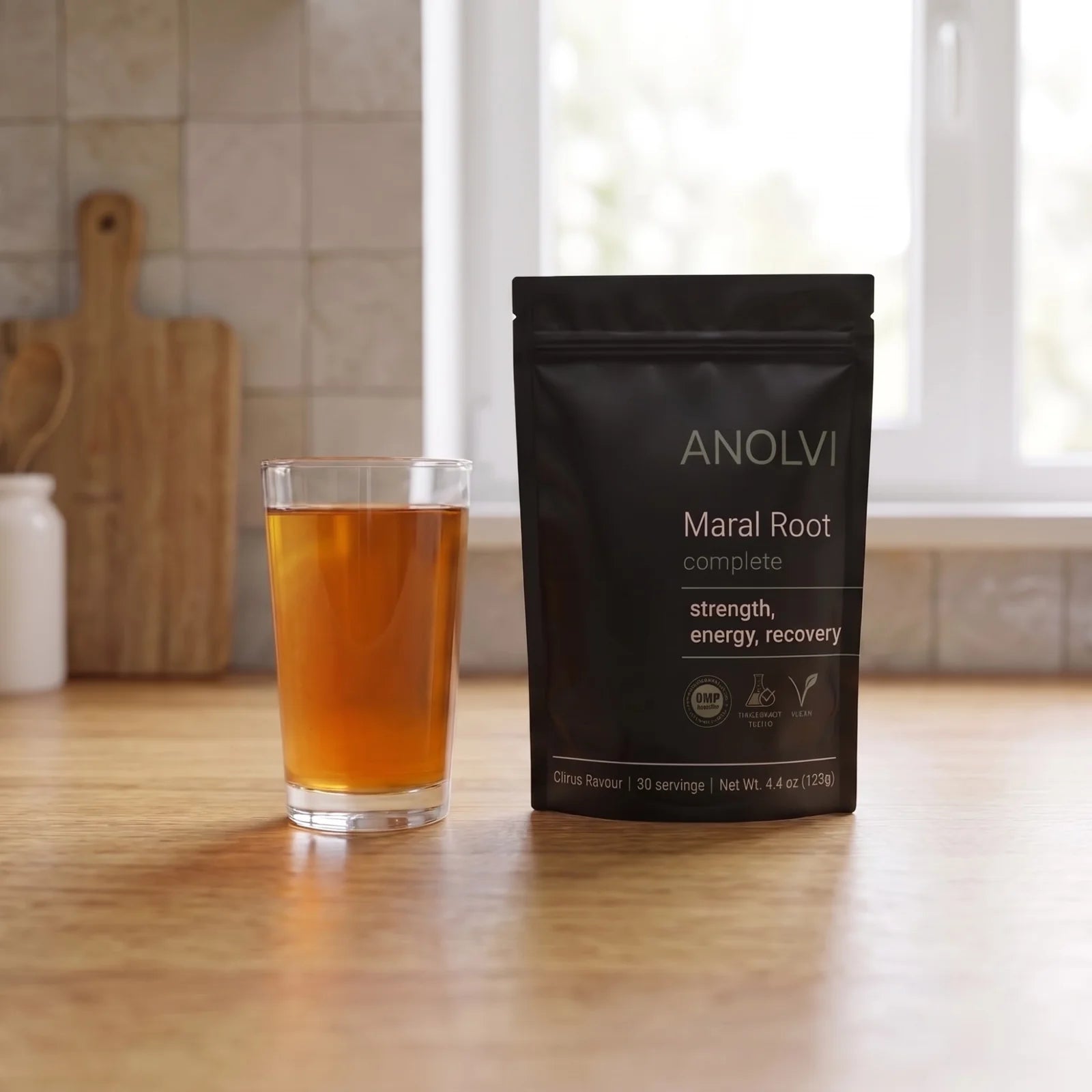 Maral Root Complete pouch next to a glass of citrus drink